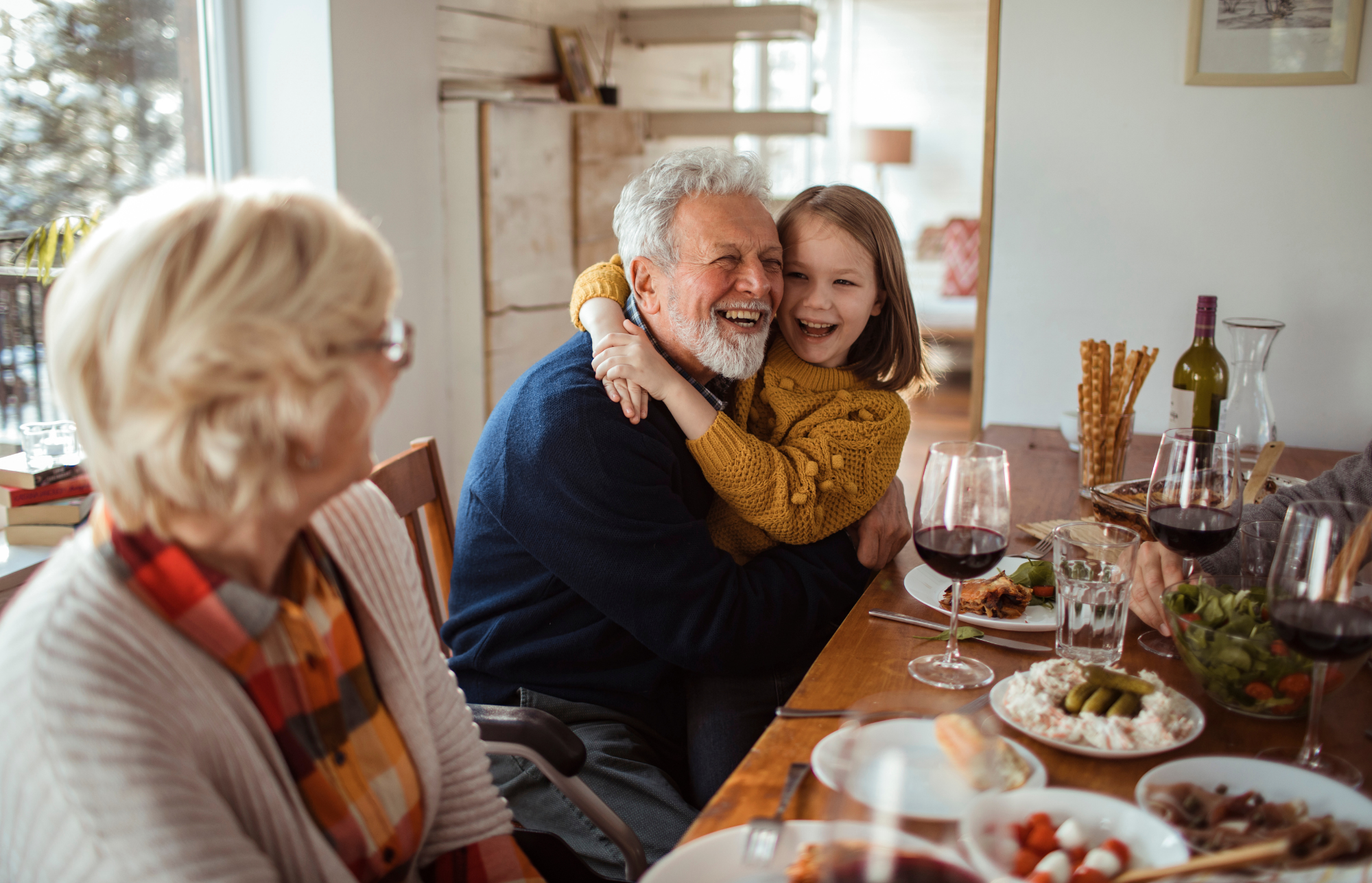 12 A happy older couple at a table with a child hugging the man.