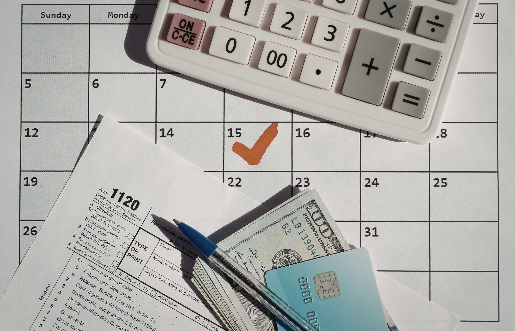25 A calendar with a date checked along with tax paperwork, money, a credit card, and a calculator.